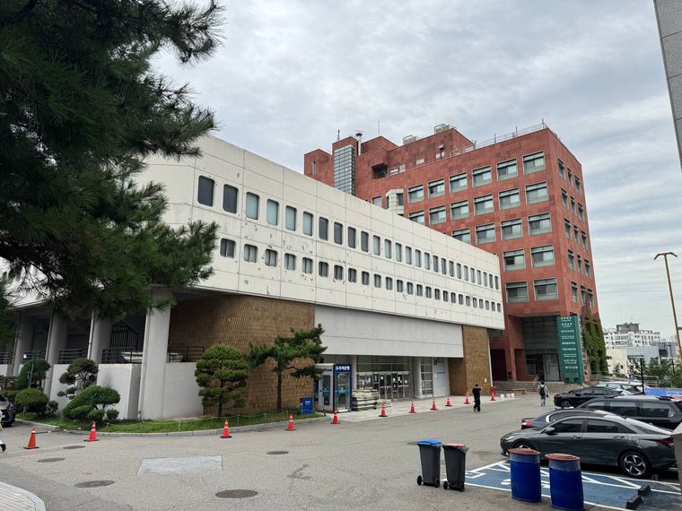 동그란 창이 줄지어 난 서강대 체육관의 흰 콘크리트 외벽, 뒤로 붉은 벽돌의 다산관 건물이 솟아 있다
