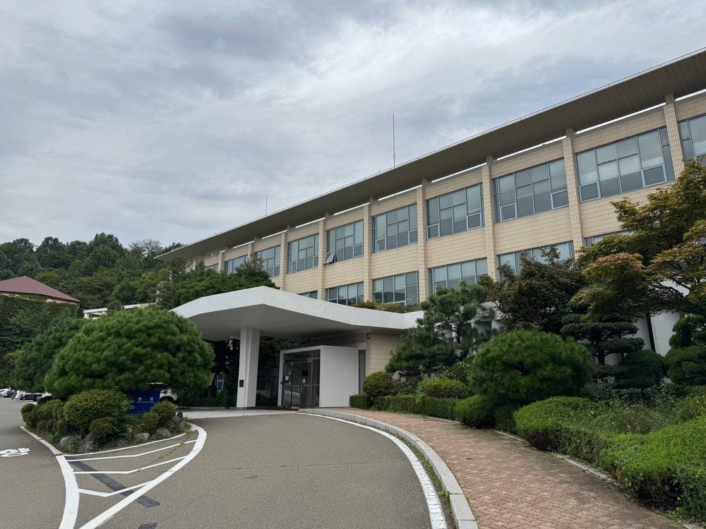 휘어진 진입로 끝에 서강대 본관 출입구가 있고 흰 차양과 소나무가 입구를 감싸고 있다